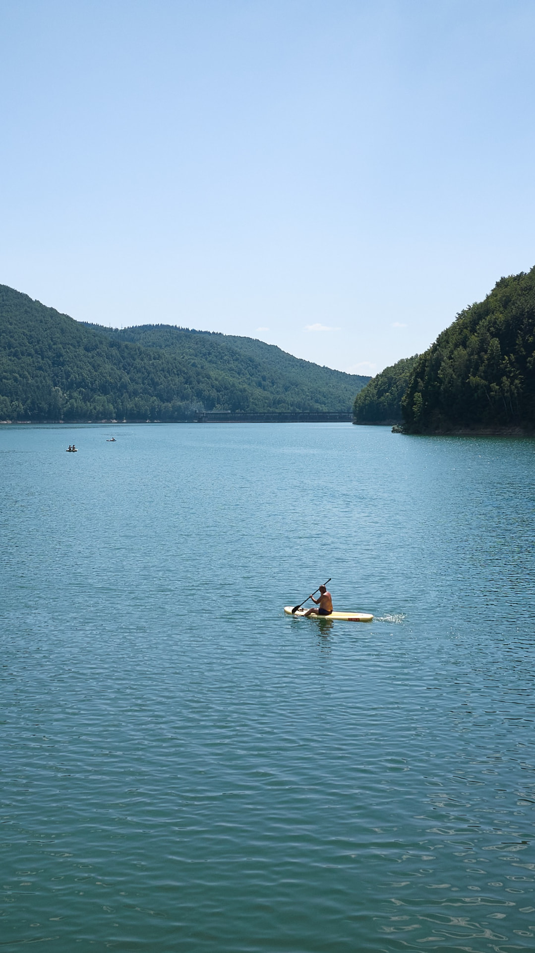 Caiac pe lac, cu dealuri împădurite în fundal