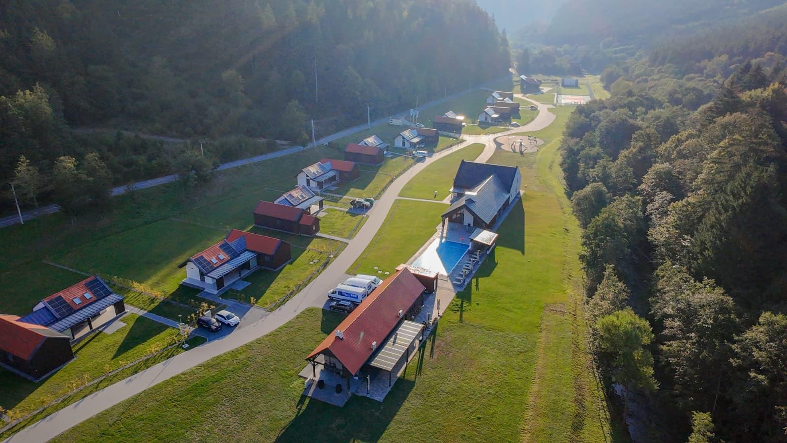 Vedere aeriană asupra vilelor și piscinei din valea împădurită