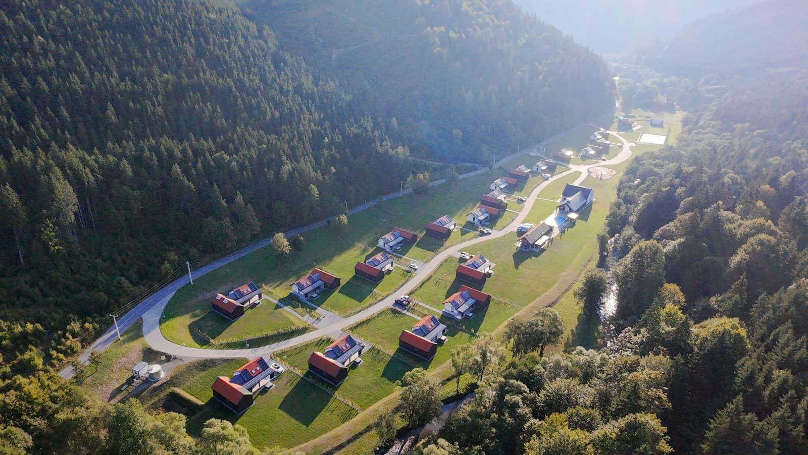 Panoramă aeriană a resortului Eskaperdo între pădure și pârâu