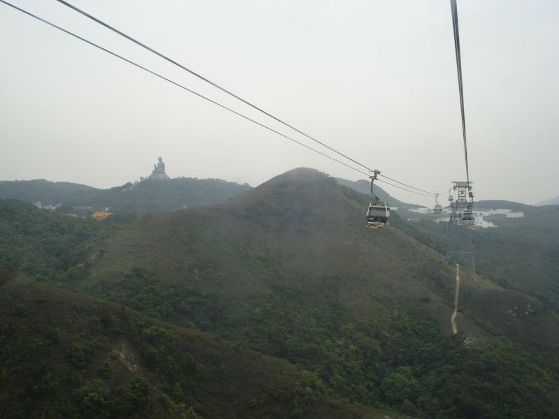 Cabine de teleferic deasupra dealurilor împădurite, sub cer cenușiu