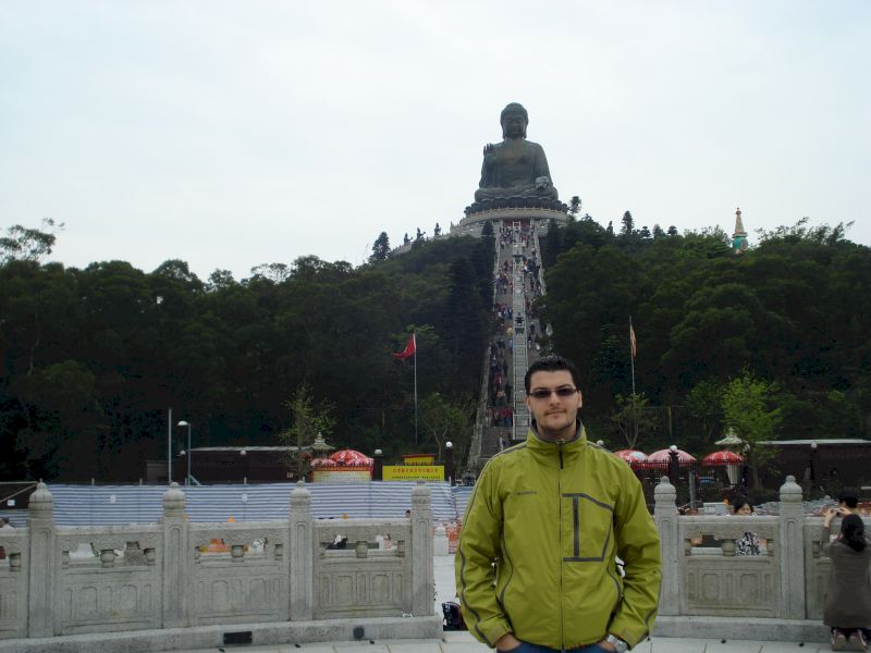 Bărbat în geacă verde în fața unei statui monumentale
