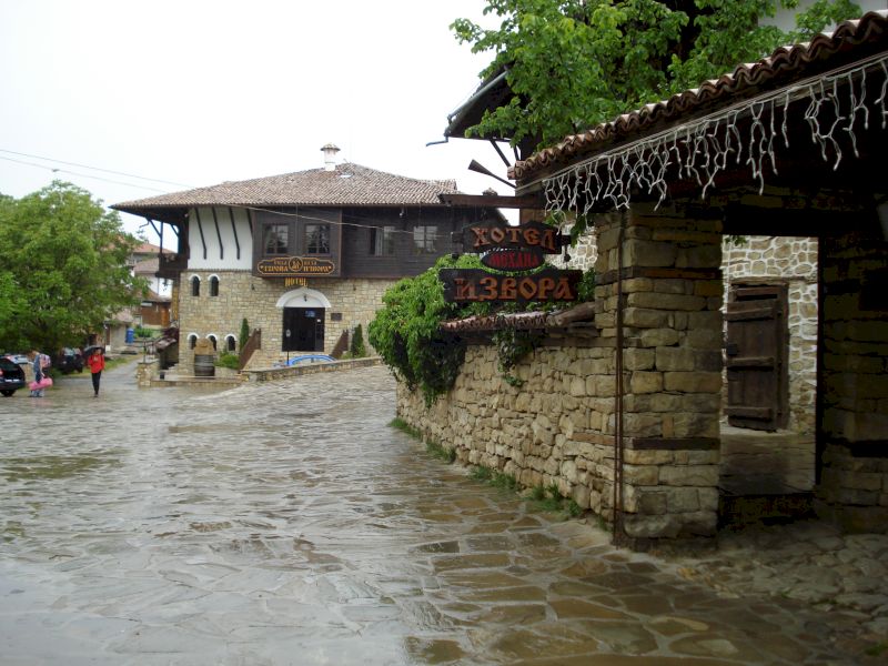 Stradă pietruită între ziduri și case cu acoperișuri largi