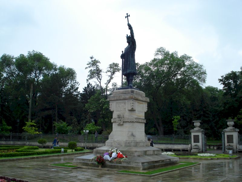 Statuie cu brațul ridicat pe soclu într-un parc