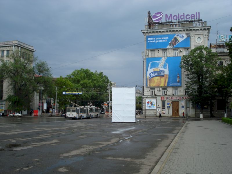 Intersecție largă cu clădire acoperită de panouri publicitare