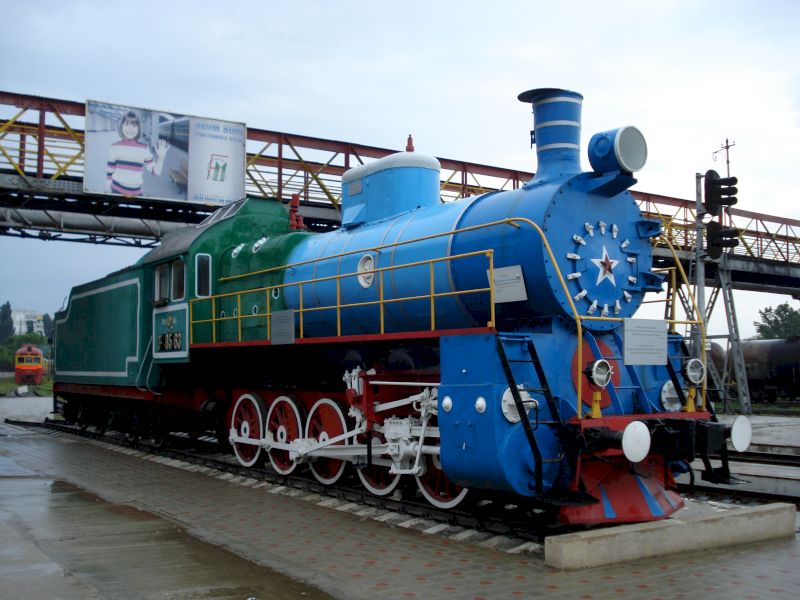Locomotivă albastră cu roți roșii expusă în aer liber