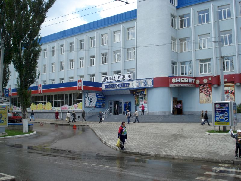 Clădire albă cu magazine la parter și accente albastre