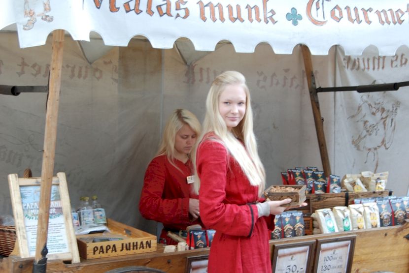 Două vânzătoare în roșu la un stand acoperit