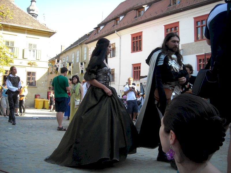 Participanți în costume întunecate pe o stradă pietruită