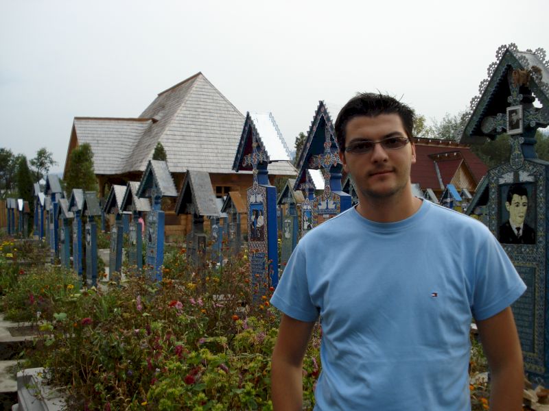 Bărbat în tricou albastru lângă cruci funerare pictate