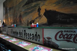 Coca Cola America de Sud Tejghea cu meniuri și reclamă Coca-Cola sub un tablou mural