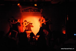 Siluete de dansatori pe o scenă luminată în portocaliu