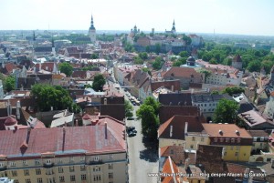 Acoperișuri roșcate și turnuri de biserici, văzute de pe o terasă înaltă.