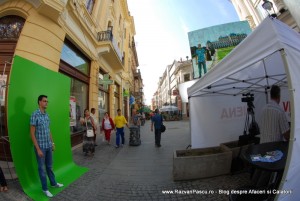 Descopera Austria 3 Instalație stradală cu fundal verde, cort alb și trecători.