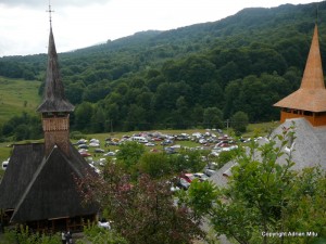 complex_monahal_Boiereni Turnuri de biserici din lemn, într-o incintă verde înconjurată de dealuri.