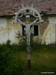 cruce_in_rogoz Cruce de piatră sculptată, în fața unui zid vechi de biserică.