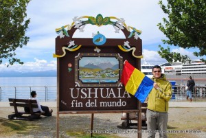 ushuaia romania razvan pascu Bărbat cu steag românesc lângă un panou Ushuaia, pe faleză.