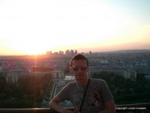 11-Pe_Turnul_Eiffel_resize Bărbat pe o platformă înaltă, cu orașul și apusul în spate.