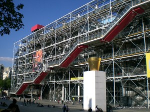 2-C._Pompidou Fațadă cu conducte exterioare și scară rulantă roșie, sub cer albastru.