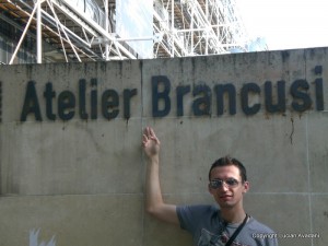 4-Intrarea_la_Atelier_Brancusi Bărbat arată spre inscripția Atelier Brancusi de pe un zid.