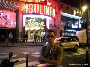 5-Moulin_Rouge Bărbat în fața cabaretului Moulin Rouge, cu reclame luminoase și taxi.