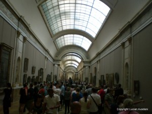 8-Aglomeratie_in_Louvre Mulțime într-o galerie lungă de muzeu, sub un luminator boltit.