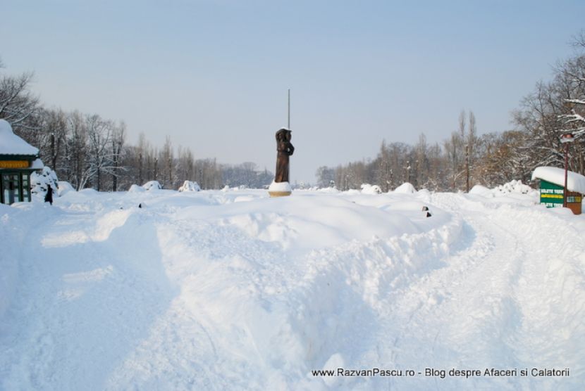 Poteci înguste duc prin troiene către o statuie aflată în depărtare.