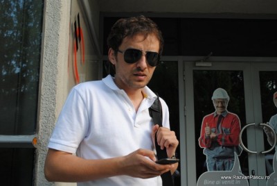 20 facebook master Bărbat cu ochelari negri și tricou alb, lângă o intrare.