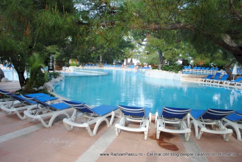 Șezlonguri albastre dispuse în semicerc la marginea piscinei.