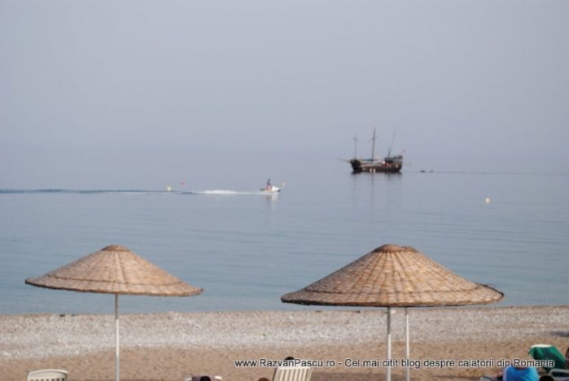 Umbrele de stuf pe plajă și ambarcațiuni în larg.