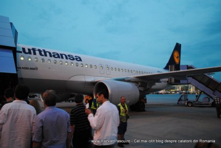 1. Lufthansa Pasageri așteaptă lângă un avion Lufthansa pe platforma aeroportului.
