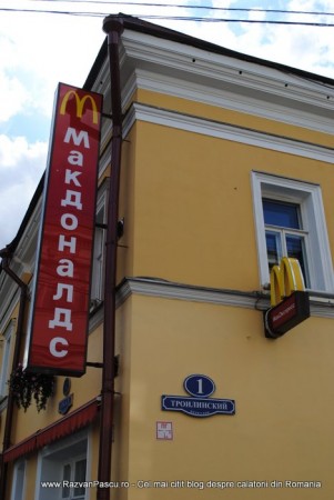 10 mc donalds rusia Firmă McDonald's verticală, cu litere chirilice, pe o clădire galbenă.