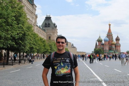 21 razvan pascu moscova Bărbat în tricou negru pe o alee, cu cupole colorate în fundal.