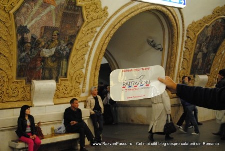 29 metrou moscova Persoană arată o foaie lângă un mozaic din metrou.