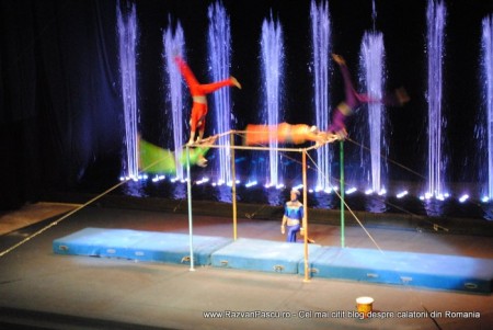 31 circ moscova Acrobați suspendați deasupra unei scene cu fântâni luminate.