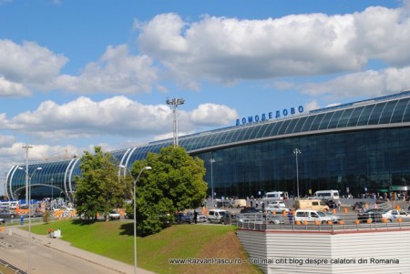 34 aeroport domodedovo Terminal aeroportuar cu fațadă vitrată curbată, sub cer cu nori.