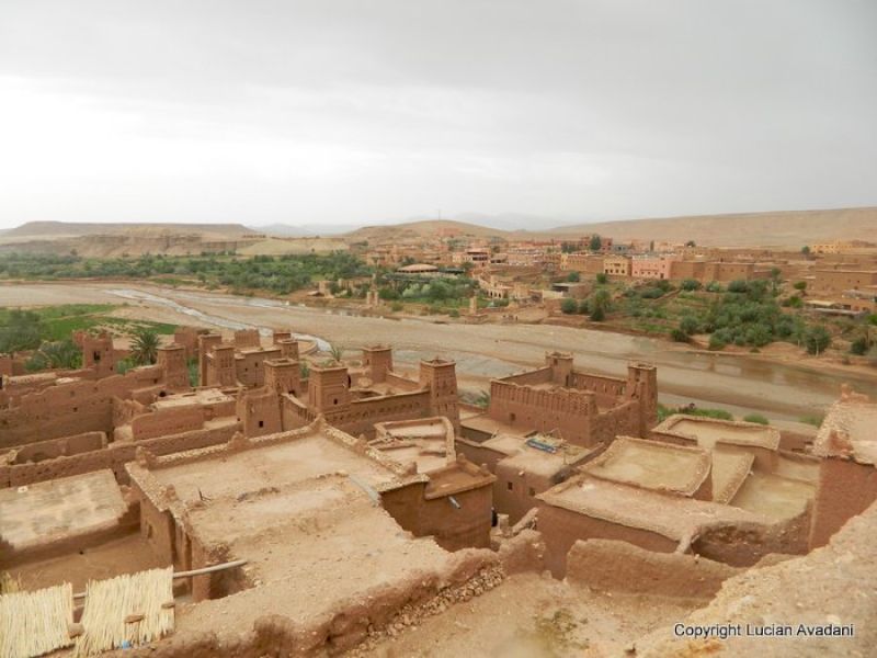Acoperișuri și ziduri de lut într-o așezare înconjurată de relief arid.