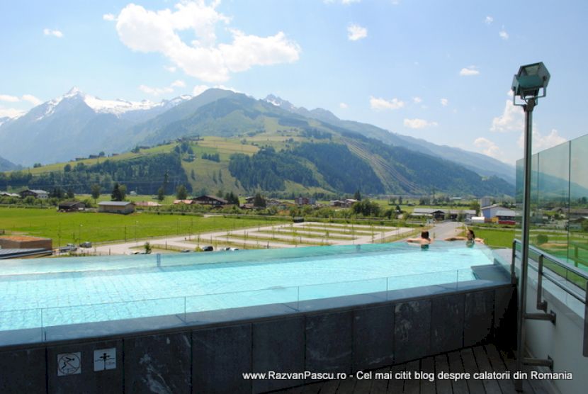Piscină panoramică sub cer cu nori, cu reflector pe stâlp lateral.