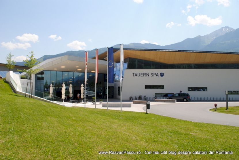 Fațada complexului Tauern SPA, dincolo de peluză și stâlpi cu steaguri.