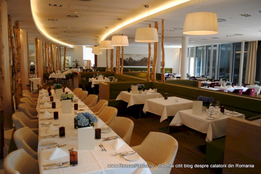 Restaurant cu mese acoperite în alb și șiruri de fotolii bej.