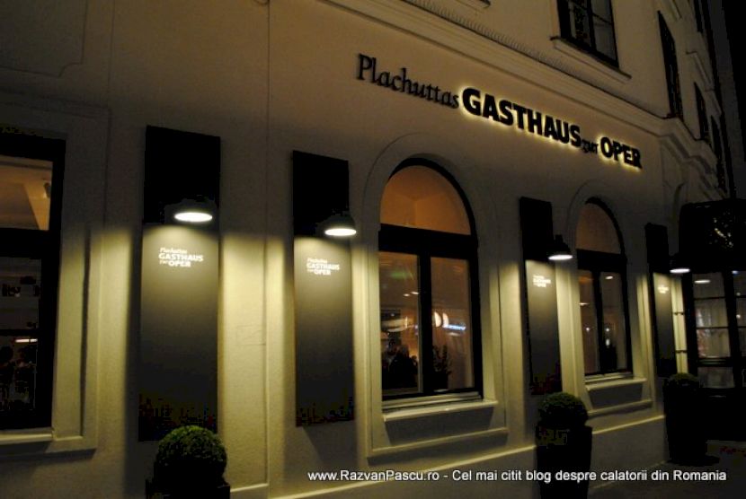 Fațadă de restaurant fotografiată noaptea, cu ferestre luminate și intrare arcuită.