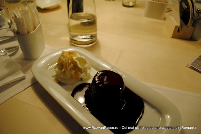 Desert rotund cu glazură de ciocolată, alături de o cupă de înghețată.