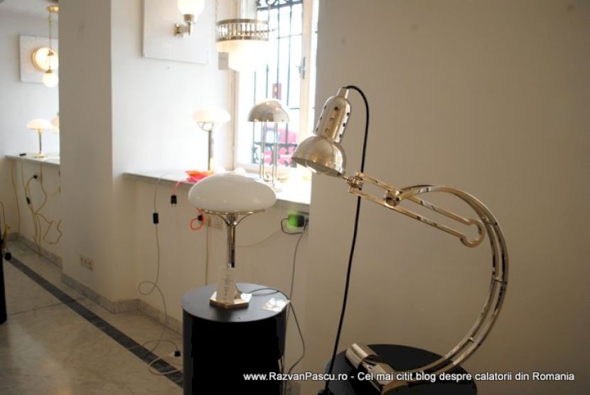 Lămpi articulate din metal, cu abajururi albe, într-un showroom luminos.