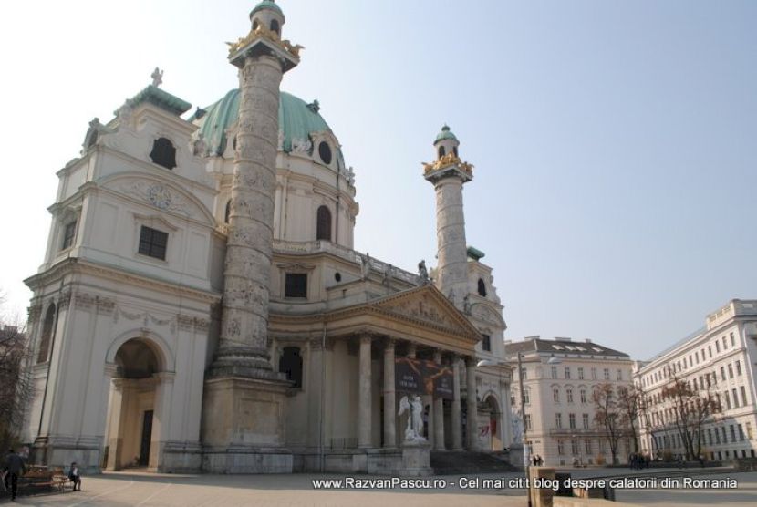 Biserică monumentală cu cupolă verde și două coloane înalte sculptate.