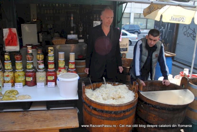 Doi vânzători în spatele unor butoaie deschise și borcane aliniate.