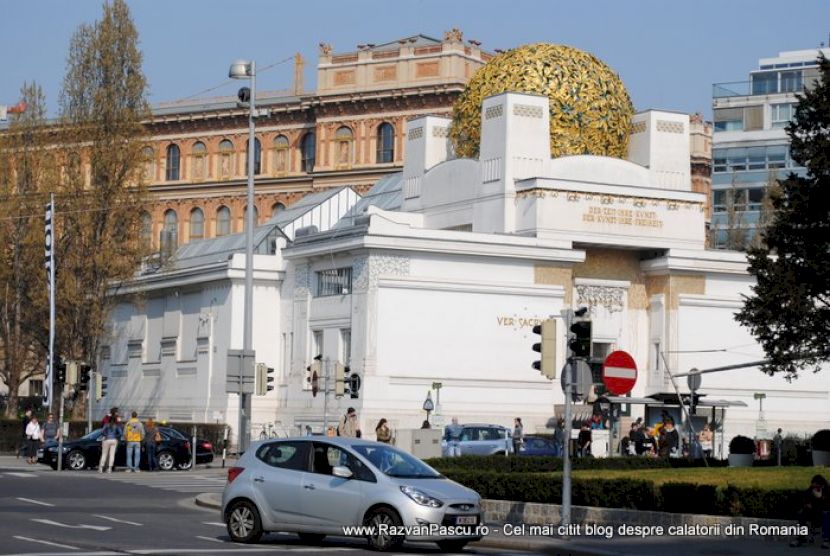 Clădire albă geometrică, cu o cupolă aurie deasupra intrării.