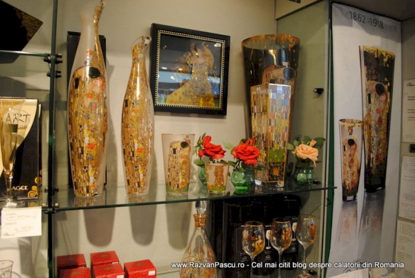Vaze înalte decorate și rame expuse într-o vitrină cu rafturi.