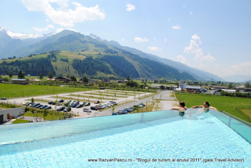 Oameni la marginea piscinei panoramice, deasupra unei parcări și a pajiștilor.