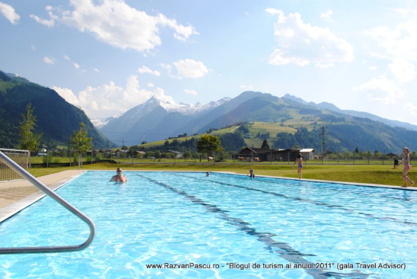 Piscină cu balustradă metalică, orientată spre pajiști și munți.