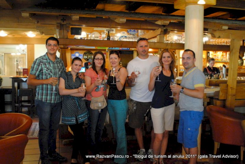 Grup de șapte persoane pozează într-un restaurant cu grinzi din lemn.