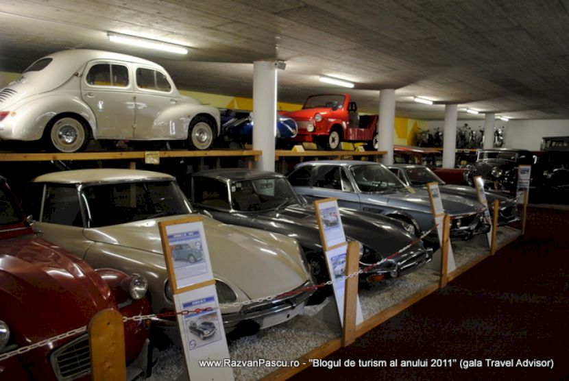 Rânduri de automobile clasice, cu un model alb pe platforma superioară.
